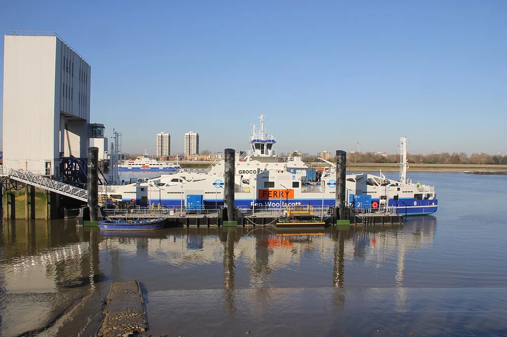 The blue and white Ben Woollacott Woolwich Ferry vessel at its riverside terminal.