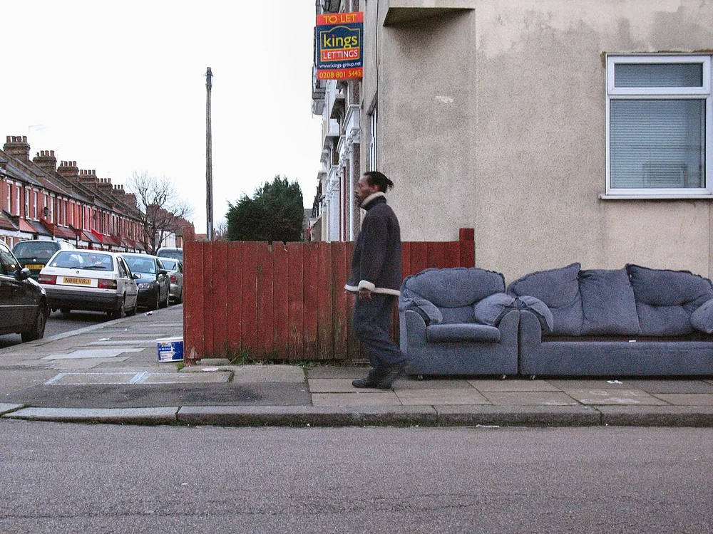 A blue upholstered sofa and matching armchair beside a London pavement.
