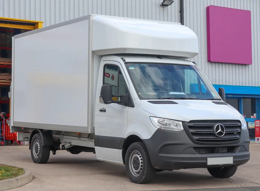 White Luton van with a tall box body and storage space above the cab